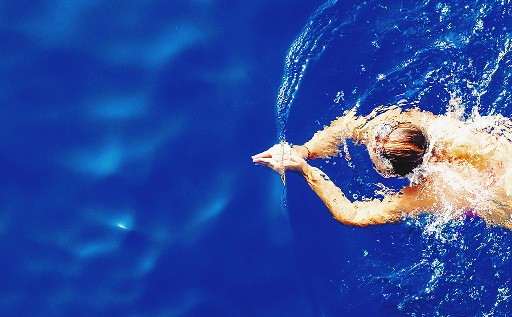 Bañista nadando en una piscina de aguas azul marino